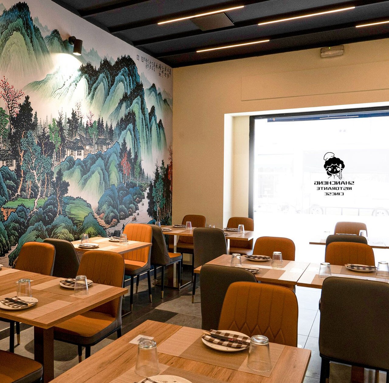 The entrance end of the room, with the mountain mural and the street windows.